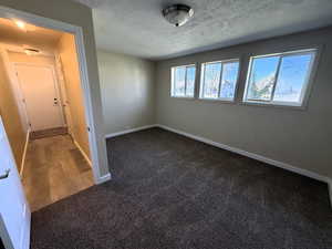 4th downstairs bedroom with dark colored carpet and a textured ceiling