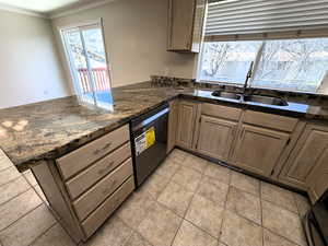 Kitchen with a peninsula, dark stone countertops, dishwashing machine, crown molding, and light tile patterned floors