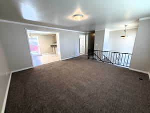 Carpeted front room featuring ornamental molding and baseboards