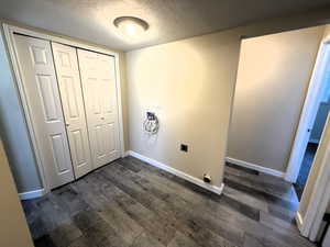 Laundry area with a textured ceiling, hookup for a washing machine, electric dryer hookup, and dark wood-style floors. Utility closet for water heater and furnace.