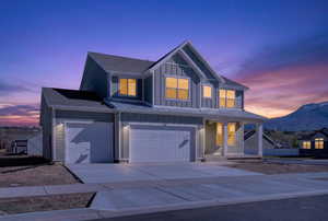 Modern farmhouse featuring board and batten siding, driveway, a porch, an attached garage, and a mountain view