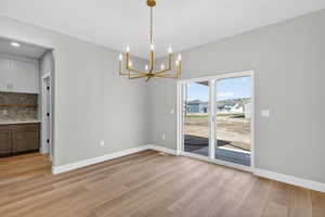 Unfurnished dining area featuring hanging lights and light wood-style floors