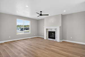 Unfurnished living room featuring a ceiling fan, light wood-style flooring, recessed lighting, and a glass covered fireplace