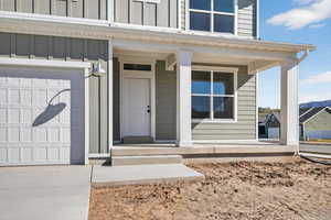 Doorway to property featuring a porch, board and batten siding, and an attached garage