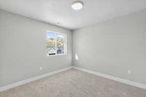 Carpeted spare room with baseboards and a textured ceiling