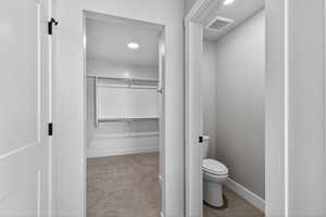 Bathroom featuring a spacious closet, recessed lighting, light colored carpet, and light tile patterned flooring