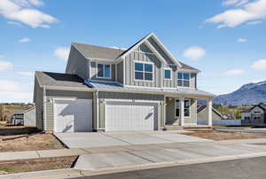 View of front facade with board and batten siding, covered porch, an attached garage, and concrete driveway