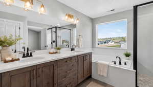 Contemporary bathroom featuring a double vanity with wood-finish cabinetry, white countertops, and matte black fixtures
