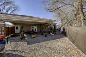 Back of house featuring a fenced backyard, stucco siding, a tile roof, and a patio area