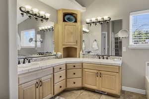 Full bathroom featuring double vanity, plenty of natural light, a garden tub, and lofted ceiling