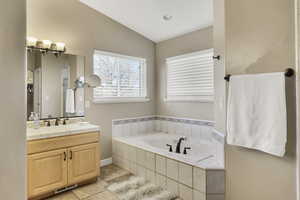 Full bathroom with vanity, a bath, and lofted ceiling
