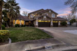 Mediterranean / spanish-style house featuring a tiled roof, stone siding, a front yard, driveway, and stucco siding