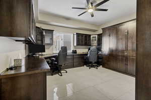 Office featuring a ceiling fan, light tile patterned flooring, and built in desk