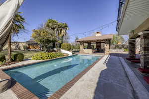 View of swimming pool with patio surround, a water slide, a fenced backyard, and exterior bar
