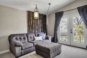 Living room featuring french doors, light colored carpet, and vaulted ceiling