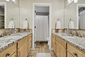Bathroom with two vanities, stone tile floors, and a shower with curtain