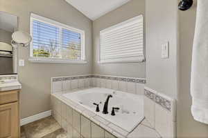 Bathroom with a jetted tub, vanity, and vaulted ceiling