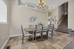 Dining space featuring stone tile floors, hanging lights, ceiling fan, and a high ceiling