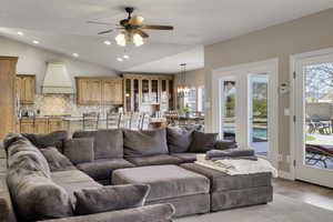 Living room featuring a ceiling fan, vaulted ceiling, and a chandelier