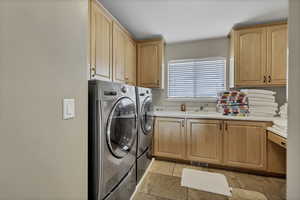 Laundry area with stone tile floors, independent washer and dryer, and cabinet space