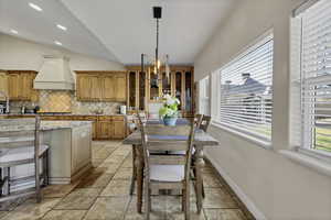Dining room with vaulted ceiling, stone tile flooring, and recessed lighting