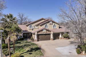Mediterranean / spanish home featuring a tiled roof, concrete driveway, stone siding, a front lawn, and an attached garage