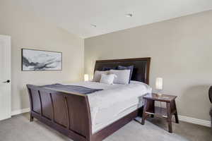 Bedroom with vaulted ceiling and light colored carpet