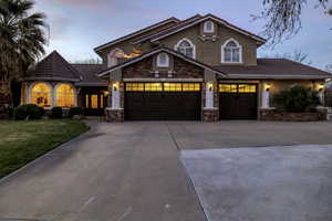 Mediterranean / spanish home featuring stone siding, driveway, stucco siding, a tile roof, and a front yard