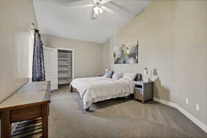 Carpeted bedroom featuring ceiling fan and lofted ceiling