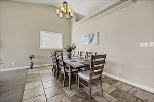 Dining room featuring stone tile floors, suspended lighting, and lofted ceiling