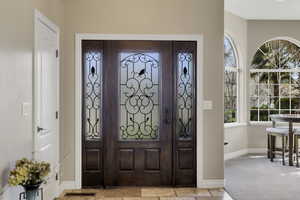 Foyer entrance with baseboards and light carpet