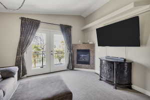 Carpeted living area featuring french doors, vaulted ceiling, and a tiled fireplace