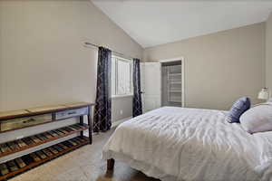Bedroom with vaulted ceiling, a spacious closet, and light colored carpet