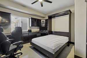Bedroom featuring an office area, light tile patterned flooring, and a ceiling fan