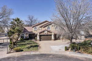 View of front facade with a tiled roof, stone siding, concrete driveway, and stucco siding