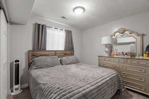 Bedroom featuring dark carpet and a textured ceiling