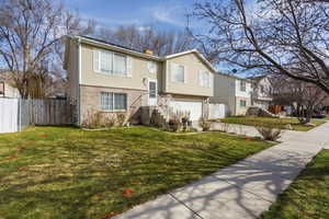 Raised ranch featuring an attached garage, a chimney, driveway, and brick siding