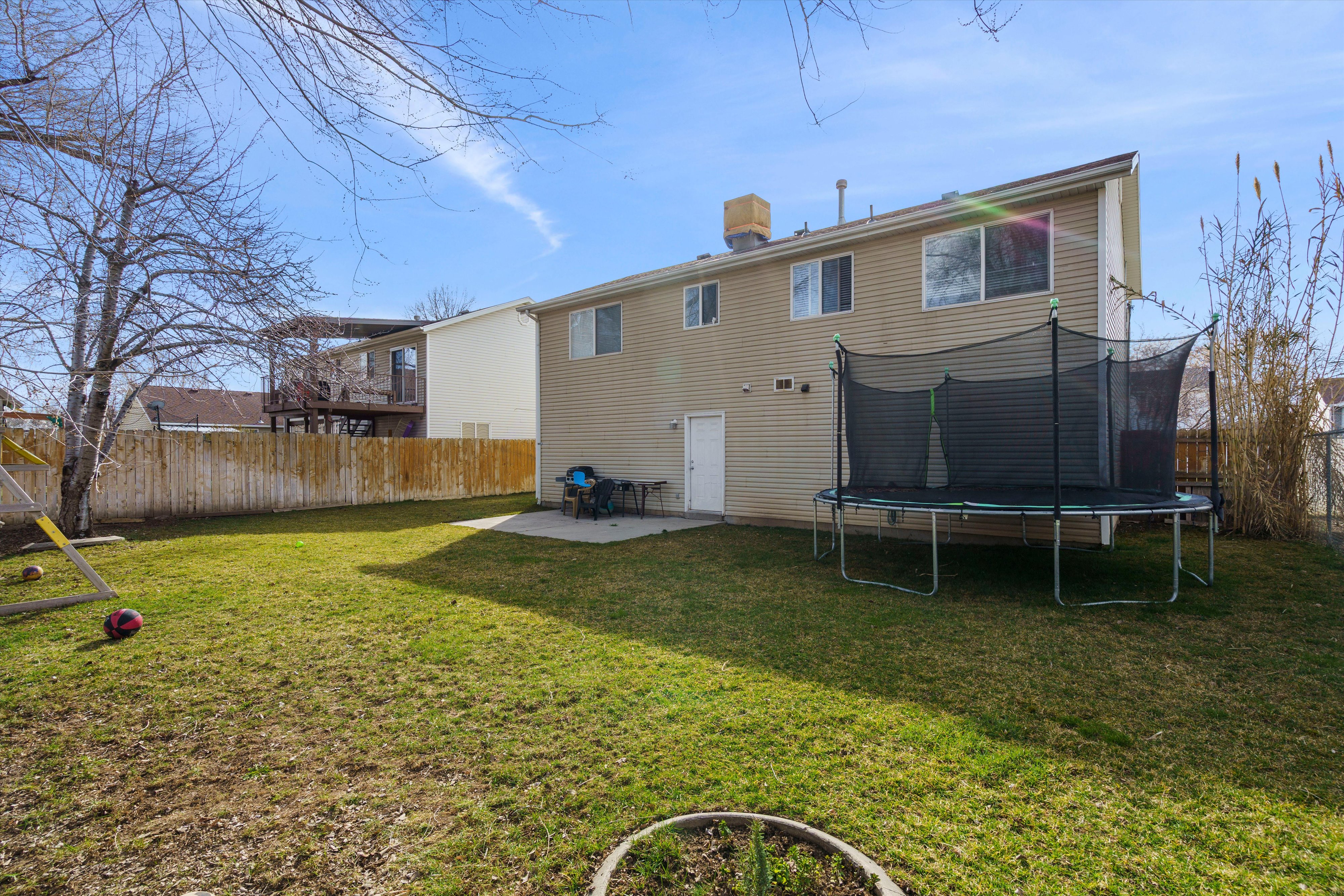 Rear view of property with a patio area, a fenced backyard, and a trampoline