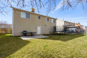 Back of house with a patio, a fenced backyard, a trampoline, and a chimney