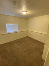 Basement bedroom #4 featuring a textured ceiling, dark carpet, and a smoke detector