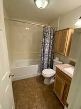 Basement Bathroom with vanity, dark tile patterned floors, and shower / bathtub combination with curtain