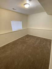 Basement bedroom #5 featuring dark carpet and a textured ceiling