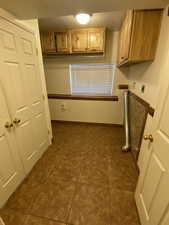 Laundry area featuring cabinet space, dark tile patterned flooring, hookup for an electric dryer, a textured ceiling, and washer hookup
