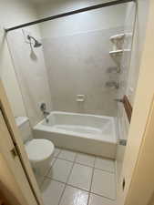 Bathroom with light tile patterned floors and washtub / shower combination