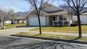 Single story home featuring concrete driveway, a garage, roof with shingles, a mountain view, and stone siding