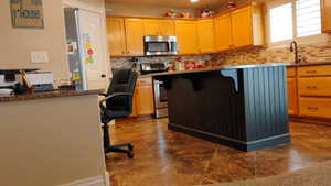 Kitchen with a breakfast bar area, stainless steel appliances, light stone counters, and backsplash