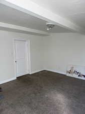 ADU Unfurnished room with dark colored carpet and baseboards