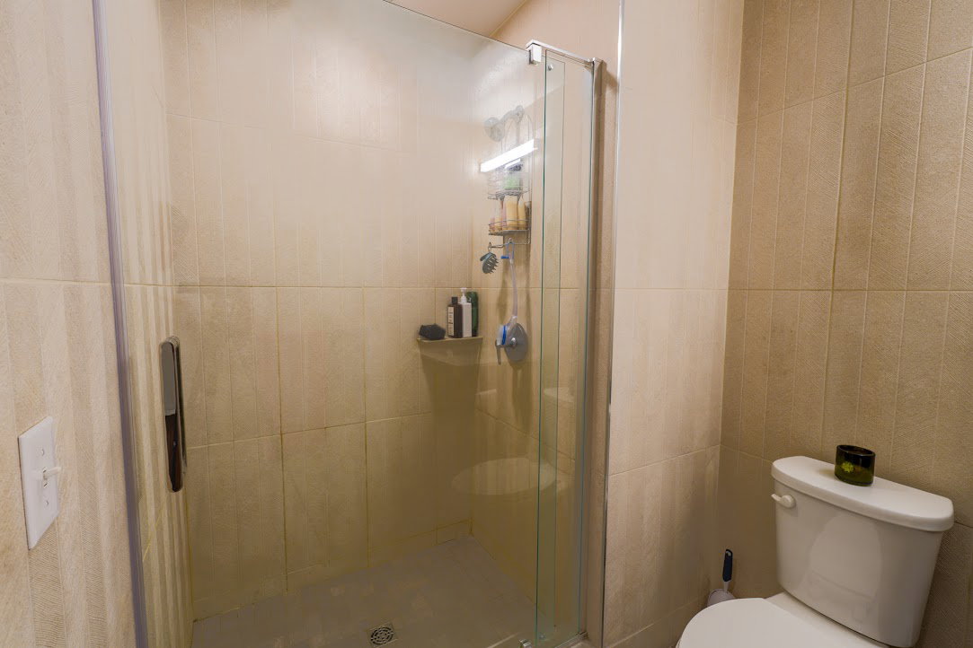 Bathroom featuring a shower stall and tile walls