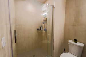Bathroom featuring a shower stall and tile walls