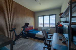 Bedroom featuring dark wood-type flooring, an accent wall, an office area, and wood walls